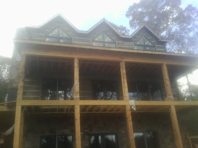 Dormers and porch framing on a large log home under construction — Roof Coating work by our crew in Northfork