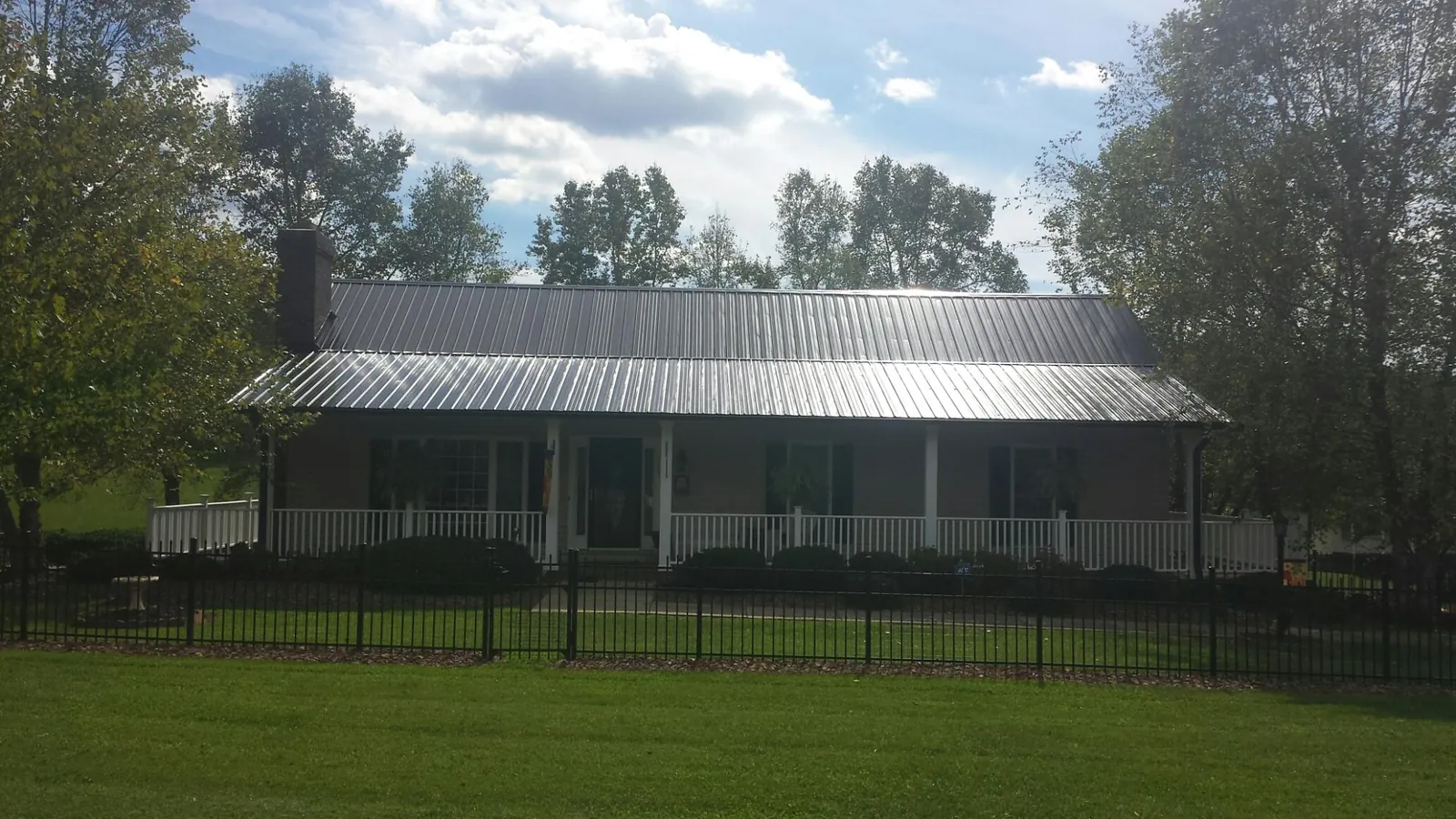 Gray metal roof on a brick ranch with a full width front porch — Gutter Guard Installation work by our crew in Northfork