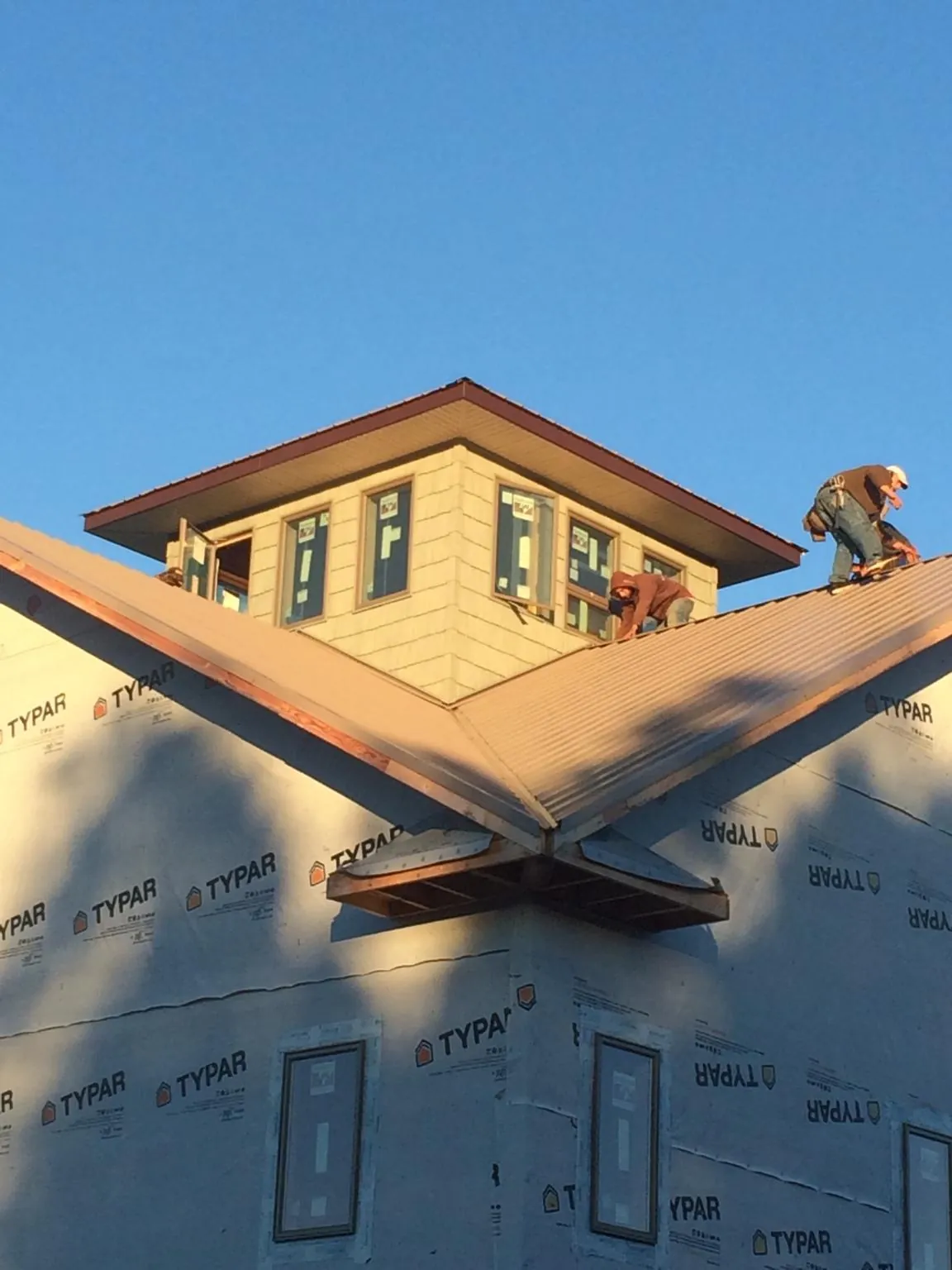 Roofers working around a rooftop cupola on a new metal roof at sunset — Roof Waterproofing in Northfork by Roofing Brothers